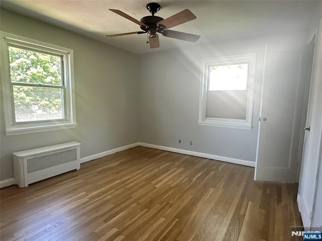 460 Heath Place, Unit 48 Hackensack, NJ 07601 - Photo 6 of 10 an empty room with wooden floor fan and windows