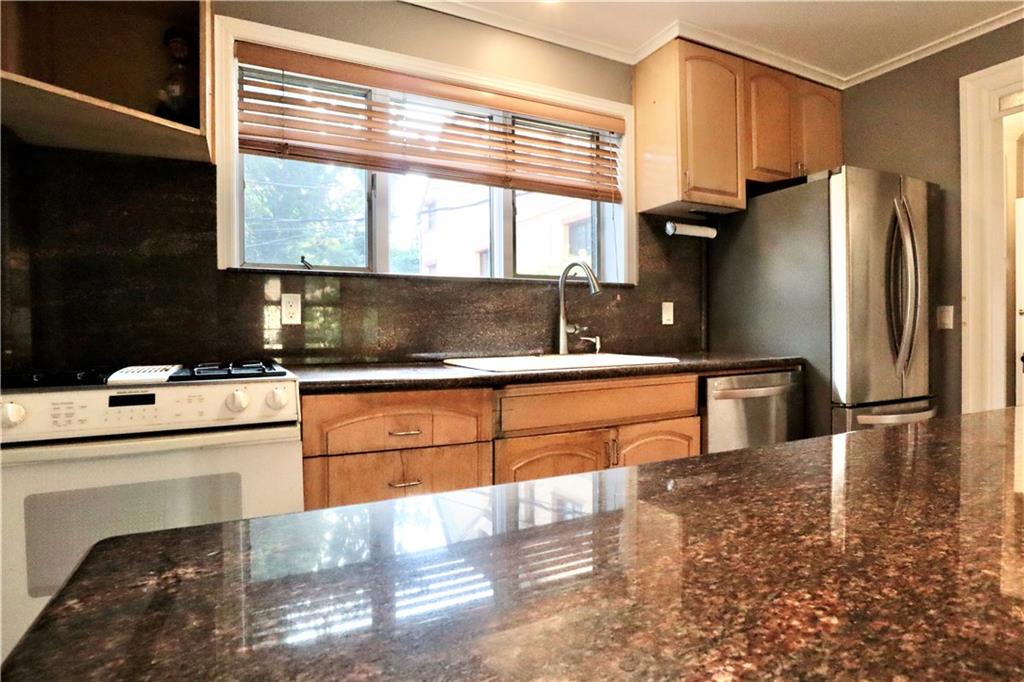24 Wendover Road Queens, NY 11375 - Photo 9 of 34 a kitchen with stainless steel appliances kitchen island granite countertop a refrigerator a stove and a sink with wooden floor