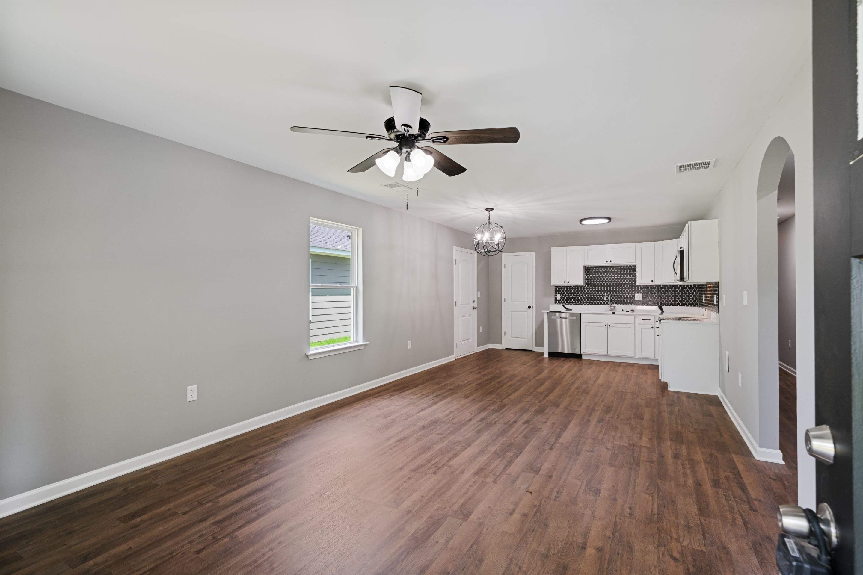 a view of empty room with wooden floor and window