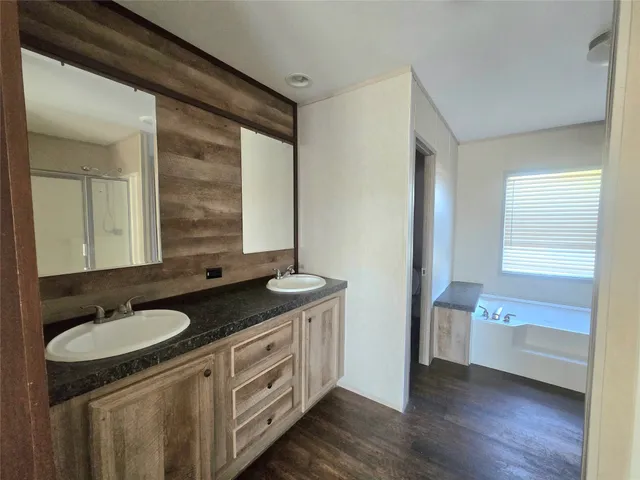 a bathroom with a granite countertop double vanity and a mirror