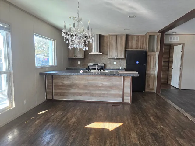 a view of a kitchen with kitchen island a sink wooden floor and a refrigerator
