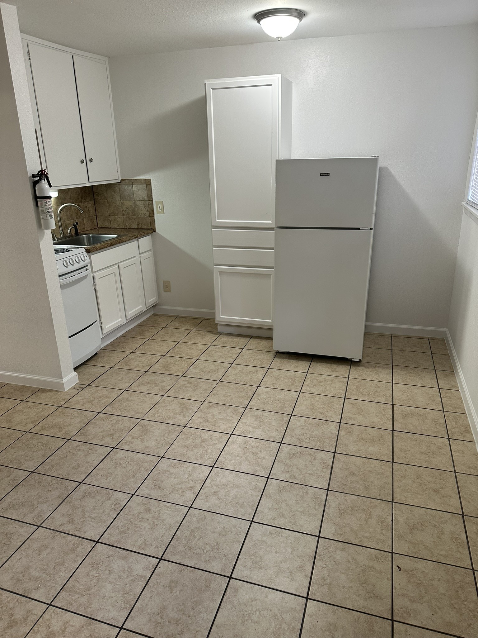 301 Avondale Street, Unit 4 Houston, TX 77006 - Photo 9 of 15 a kitchen with a stove a refrigerator and white cabinets