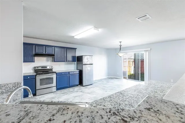 a kitchen with stainless steel appliances granite countertop a stove a sink dishwasher a refrigerator and a oven with wooden floor