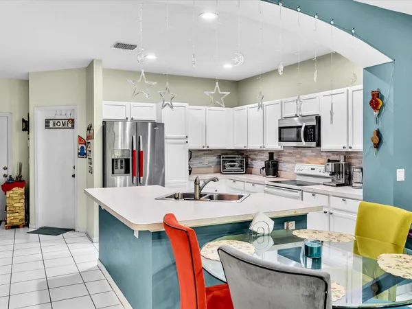 a kitchen with stainless steel appliances kitchen island granite countertop a refrigerator a stove a microwave oven a sink dishwasher and white cabinets with wooden floor