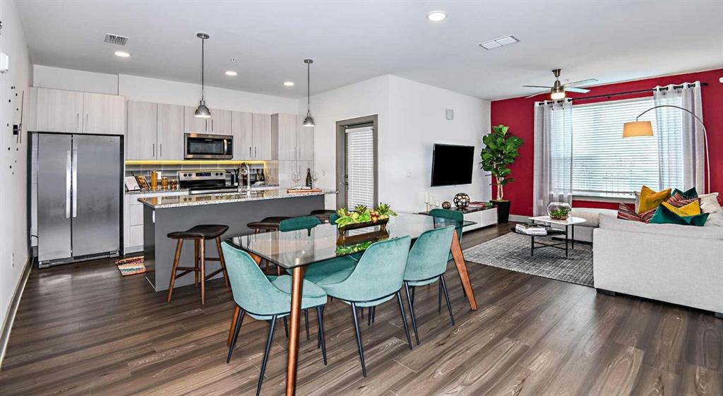 1040 Jamison Loop, Unit REVIVE Kissimmee, FL 34744 - Photo 2 of 18 a kitchen with stainless steel appliances a dining table chairs stove refrigerator and microwave