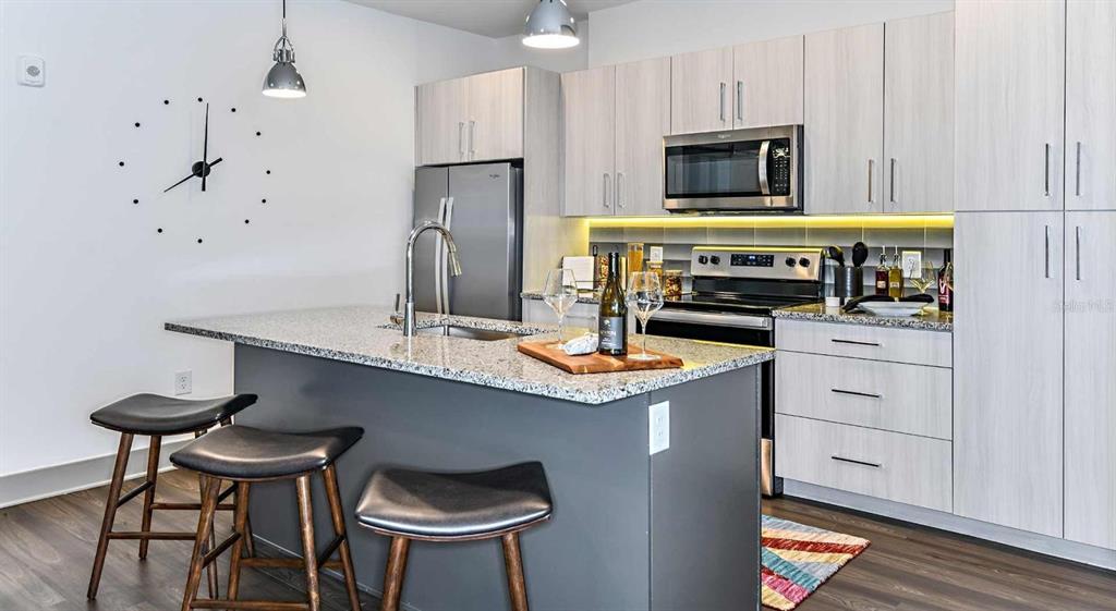 1040 Jamison Loop, Unit REVIVE Kissimmee, FL 34744 - Photo 4 of 18 a kitchen with stainless steel appliances a stove a sink and a refrigerator