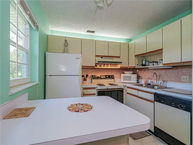 a kitchen with stainless steel appliances granite countertop a refrigerator sink stove and white cabinets