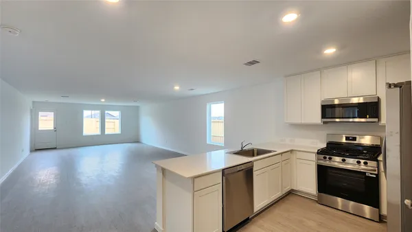 a kitchen with stainless steel appliances kitchen island granite countertop a stove a sink and a refrigerator