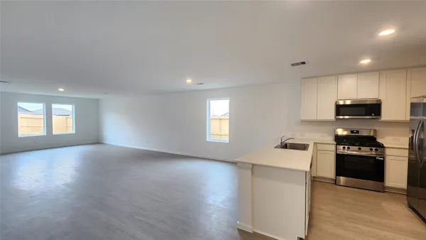 a kitchen with granite countertop a stove top oven a sink dishwasher and a refrigerator with wooden floor