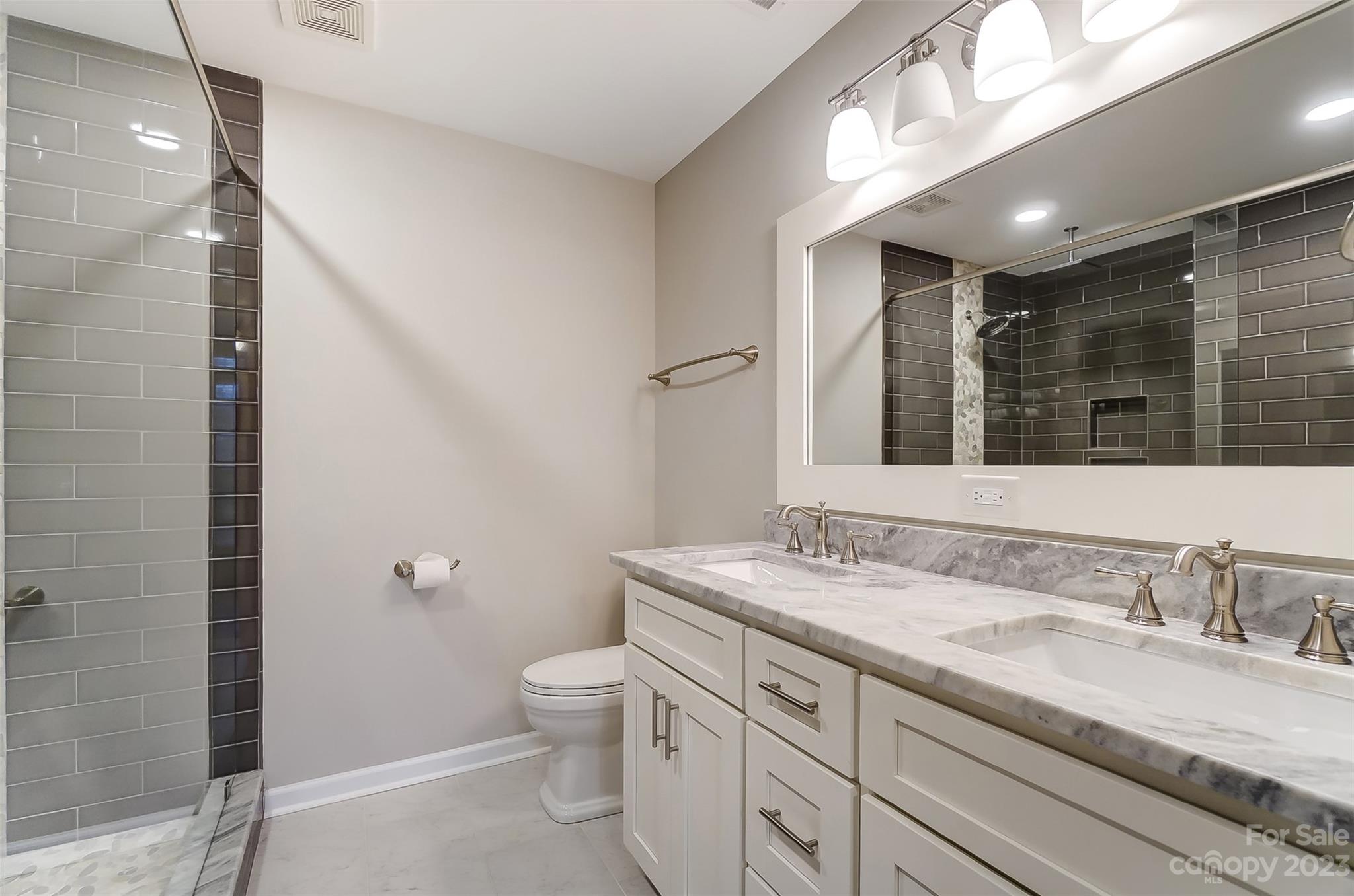 231 Lincoln Street Charlotte, NC 28203 - Photo 37 of 48 a bathroom with a granite countertop sink a mirror and a toilet