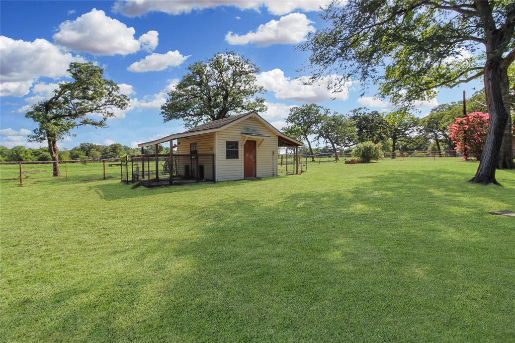 1001 Sandy Ridge Road Scurry, TX 75158 - Photo 31 of 35 Detached outbuilding with light-colored siding and a brown shingled roof, featuring a covered porch with dark wood railings