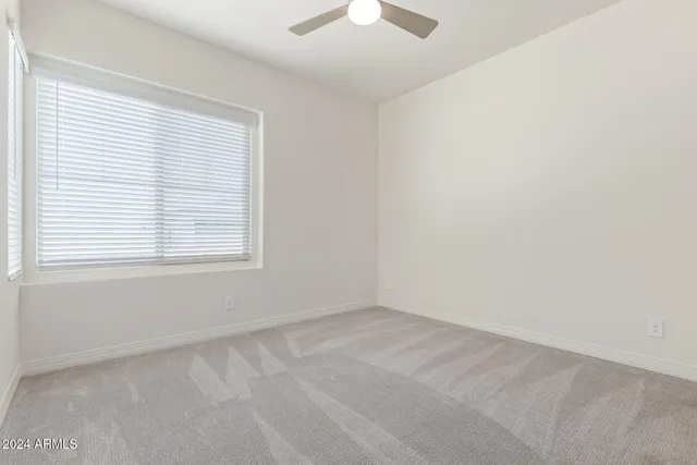 an empty room with a window and a fan