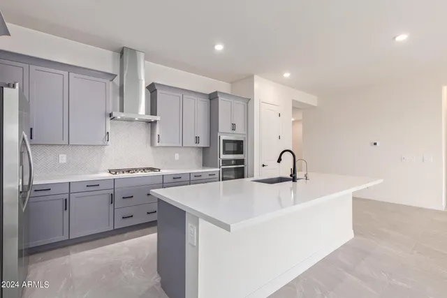 a large kitchen with stainless steel appliances lots of white cabinets
