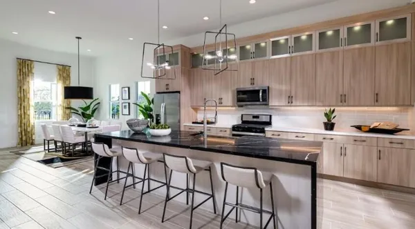 a kitchen with stainless steel appliances granite countertop a stove top oven a sink a dining table and chairs with wooden floor