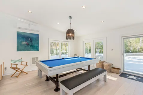 a living room with furniture pool table and windows
