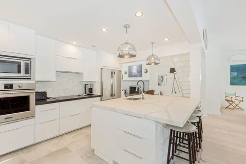 a large kitchen with granite countertop a white stove top oven a sink dishwasher and a refrigerator with wooden floor