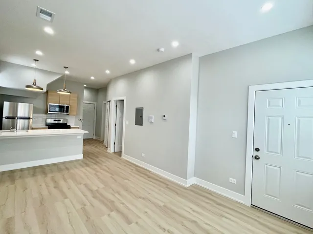 a view of a kitchen with kitchen island wooden floor center island and stainless steel appliances