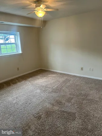 an empty room with a chandelier fan and windows
