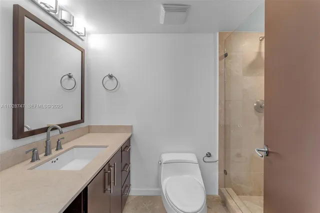 a bathroom with a granite countertop sink a toilet and shower
