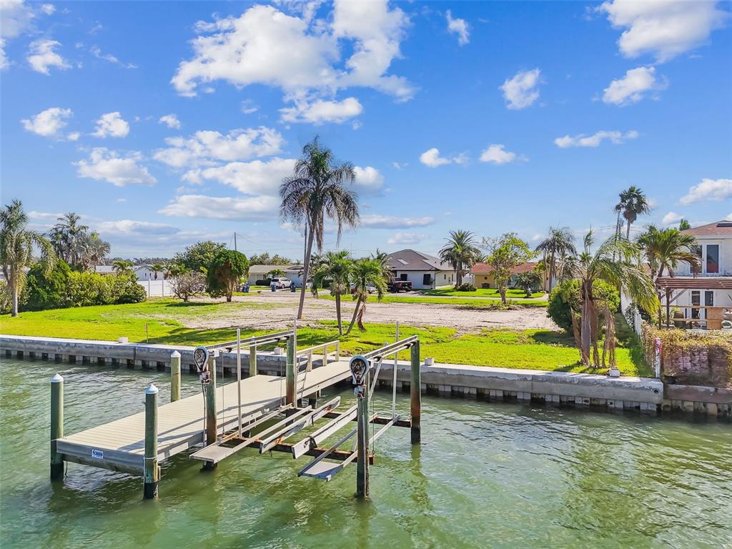 568 Johns Pass Avenue Madeira Beach, FL 33708 - Photo 7 of 36 a view of a swimming pool with a lawn chairs under an umbrella and yard