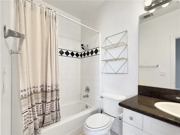 a bathroom with a granite countertop bathtub sink vanity mirror and toilet
