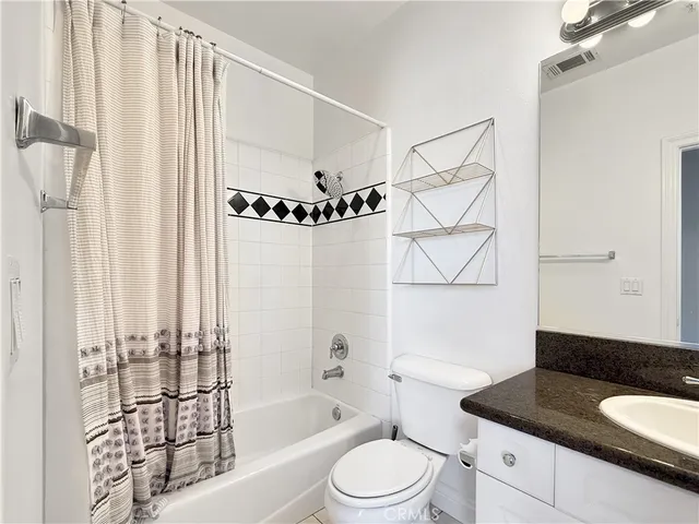 a bathroom with a granite countertop bathtub sink vanity mirror and toilet