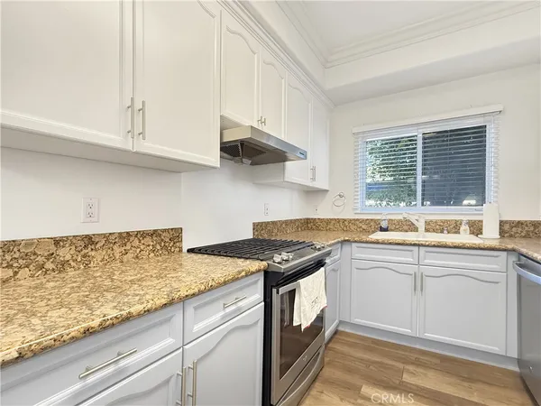 a kitchen with granite countertop a sink a stove and cabinets