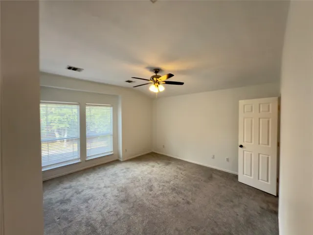 an empty room with windows and fan