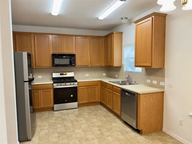 a kitchen with stainless steel appliances granite countertop a stove top oven a sink and dishwasher a refrigerator with wooden floor