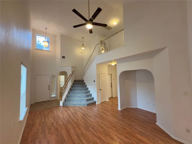 an empty room with wooden floor and a ceiling fan