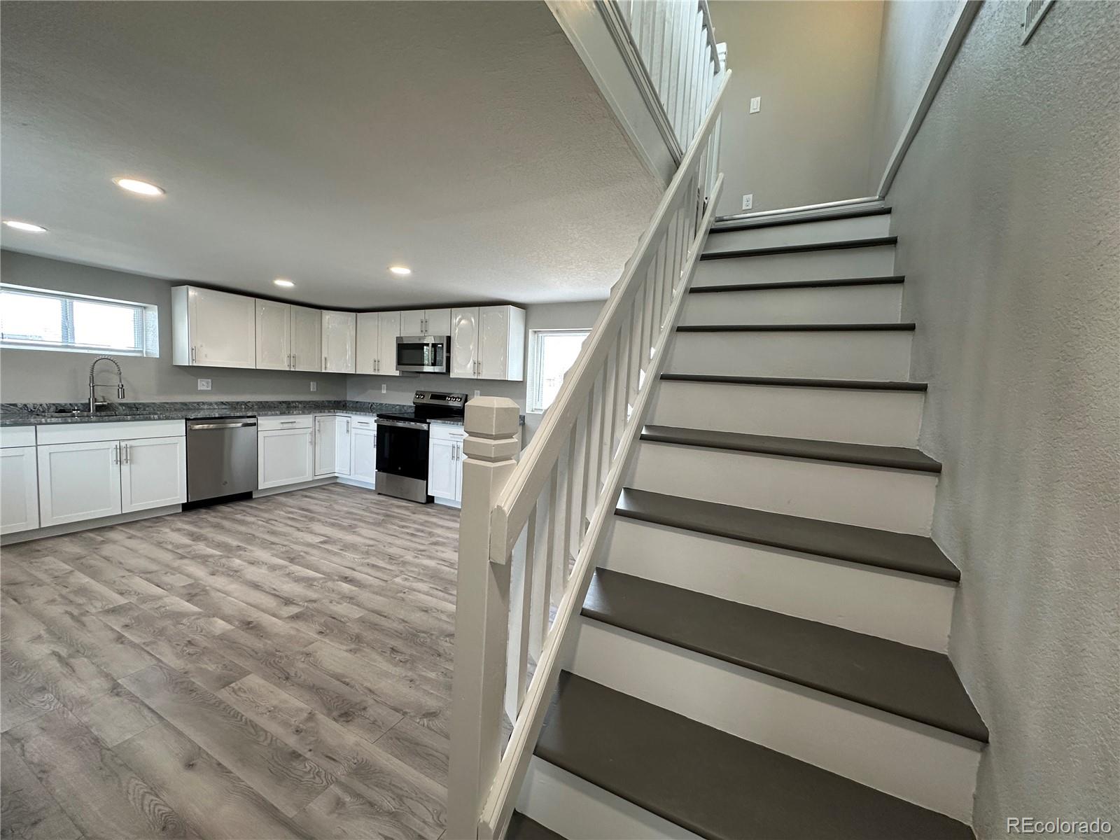 Undisclosed Address Pueblo, CO 81006 - Photo 9 of 27 a large white kitchen with wooden floors and stainless steel appliances