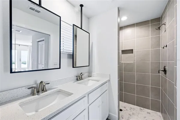 a bathroom with a double vanity sink mirror and shower