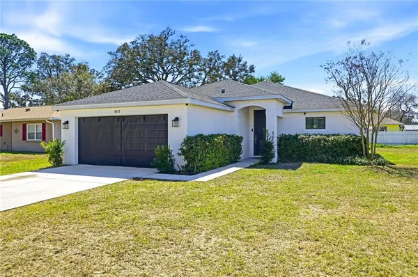 a view of a house with a yard and large tree