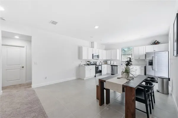 a kitchen with stainless steel appliances a table and chairs in it