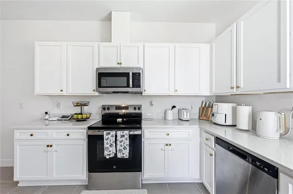 a kitchen with granite countertop white cabinets sink and stainless steel appliances