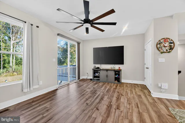 a view of a livingroom with a flat screen tv wooden floor and a ceiling fan