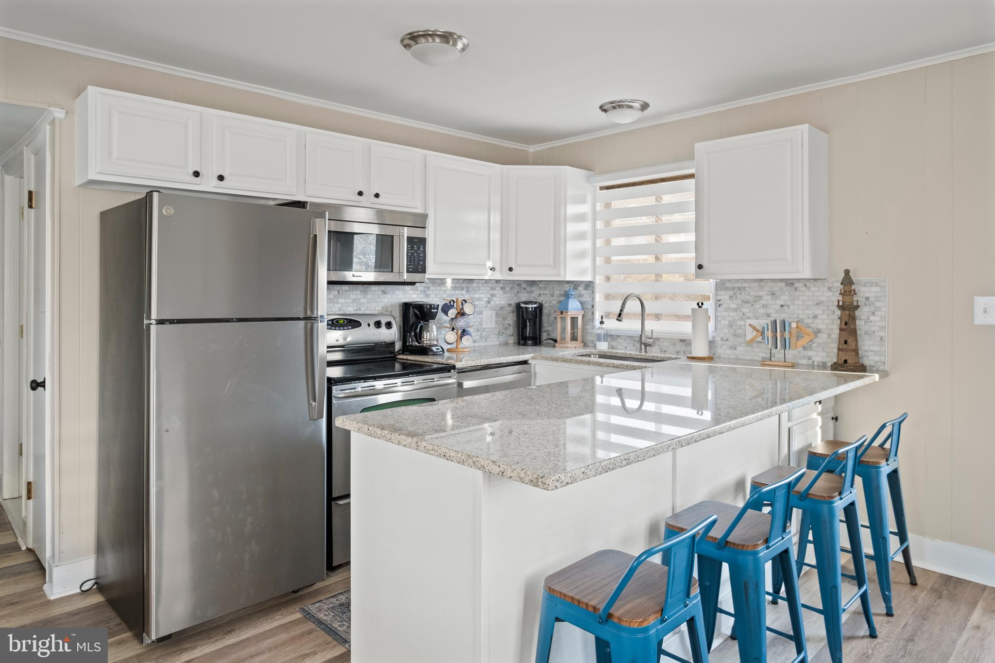 a kitchen with stainless steel appliances granite countertop a refrigerator a sink a stove a dining table and chairs