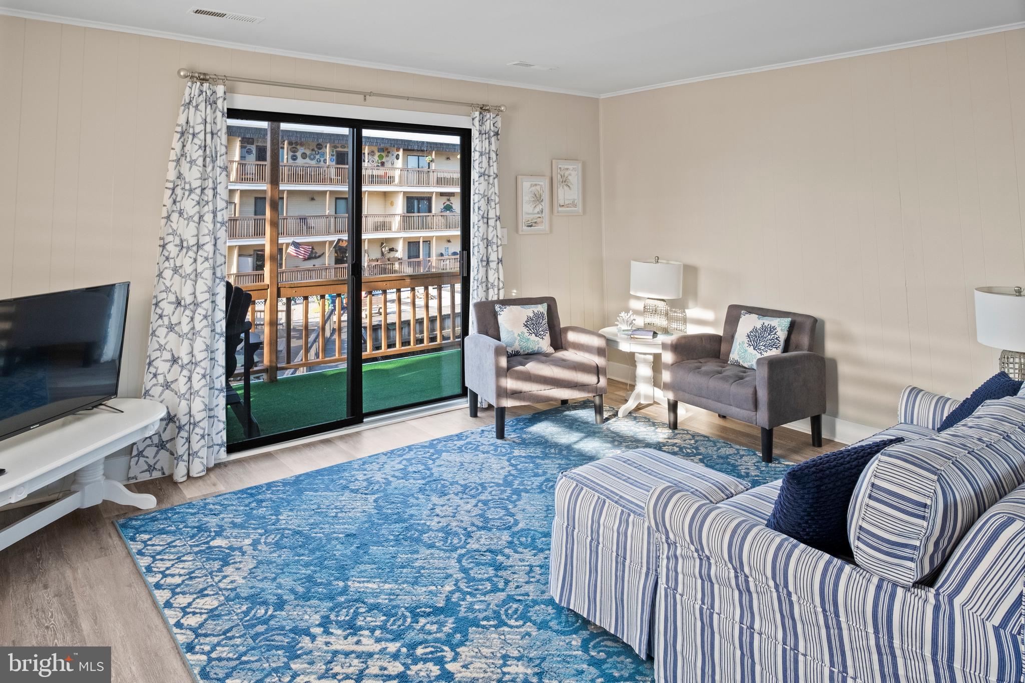 170 Captains Quarters Road, Unit 201 Ocean City, MD 21842 - Photo 44 of 65 a living room with furniture a flat screen tv and a floor to ceiling window