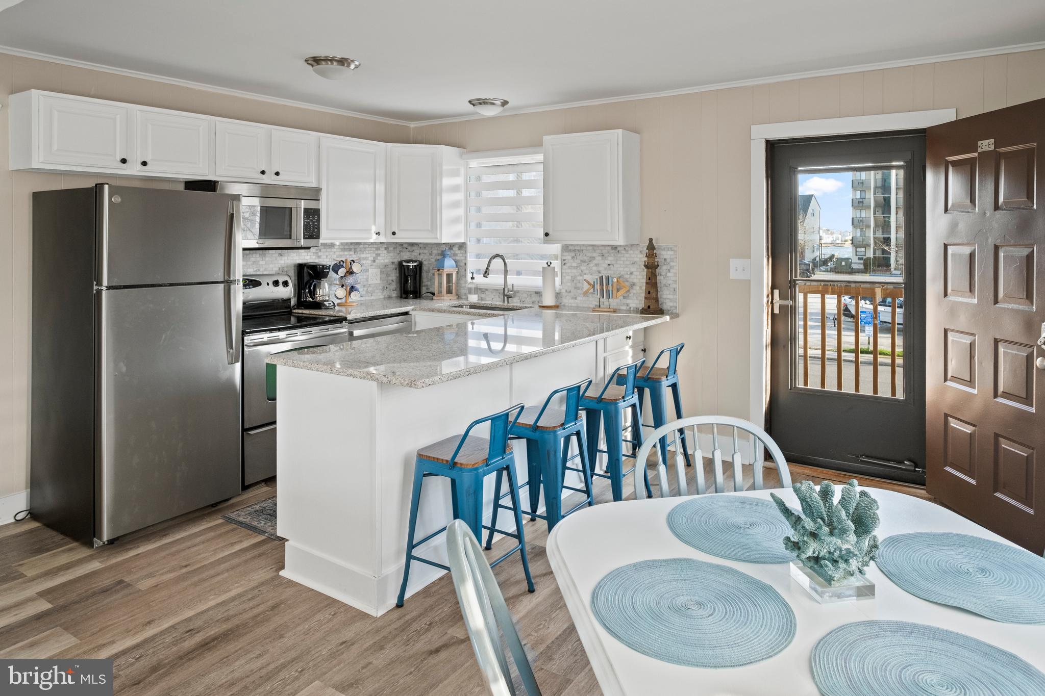 170 Captains Quarters Road, Unit 201 Ocean City, MD 21842 - Photo 51 of 65 a kitchen with stainless steel appliances granite countertop a dining table chairs a refrigerator and a granite counter tops