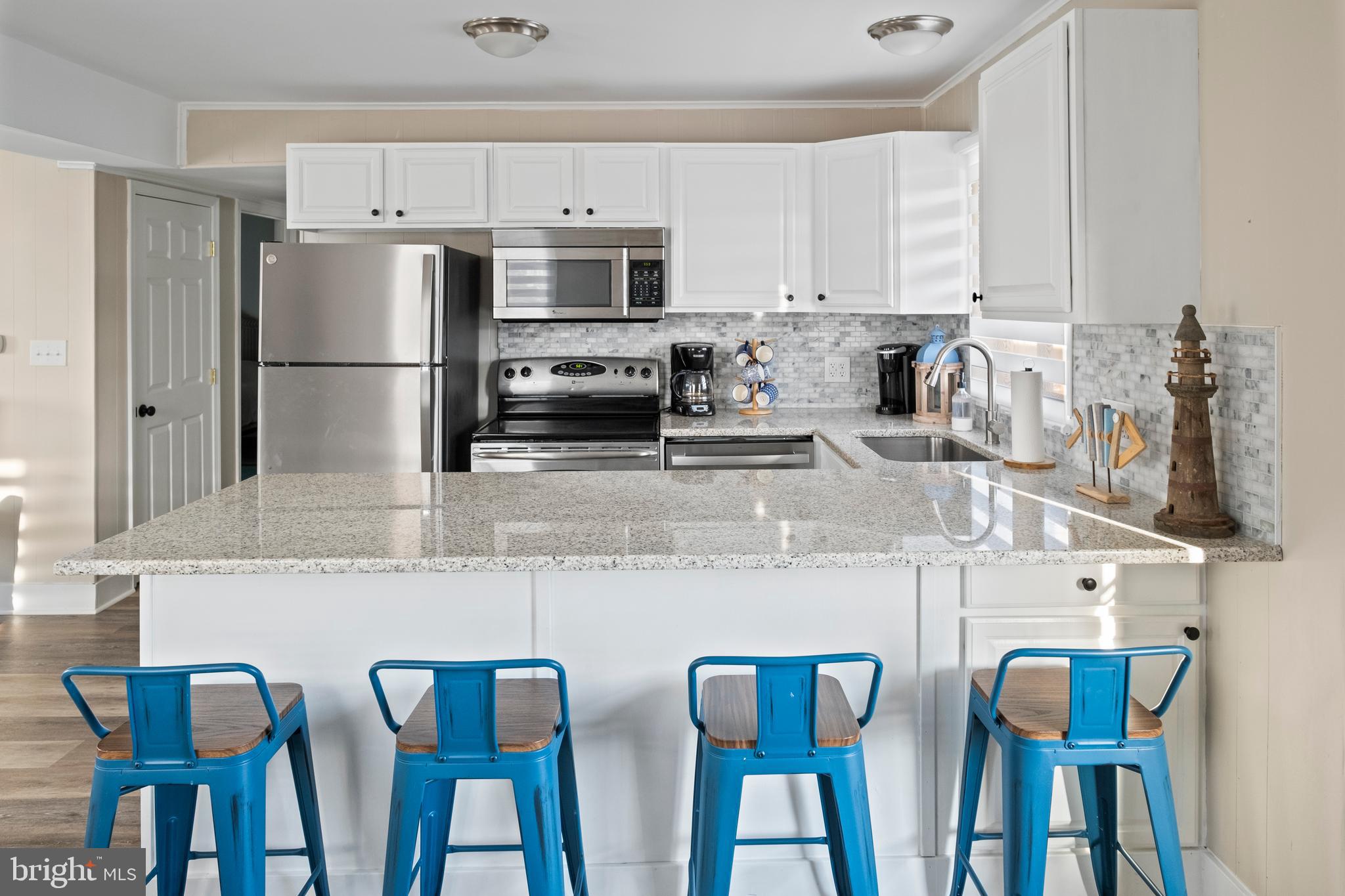 170 Captains Quarters Road, Unit 201 Ocean City, MD 21842 - Photo 54 of 65 a kitchen with stainless steel appliances granite countertop a dining table chairs refrigerator and sink