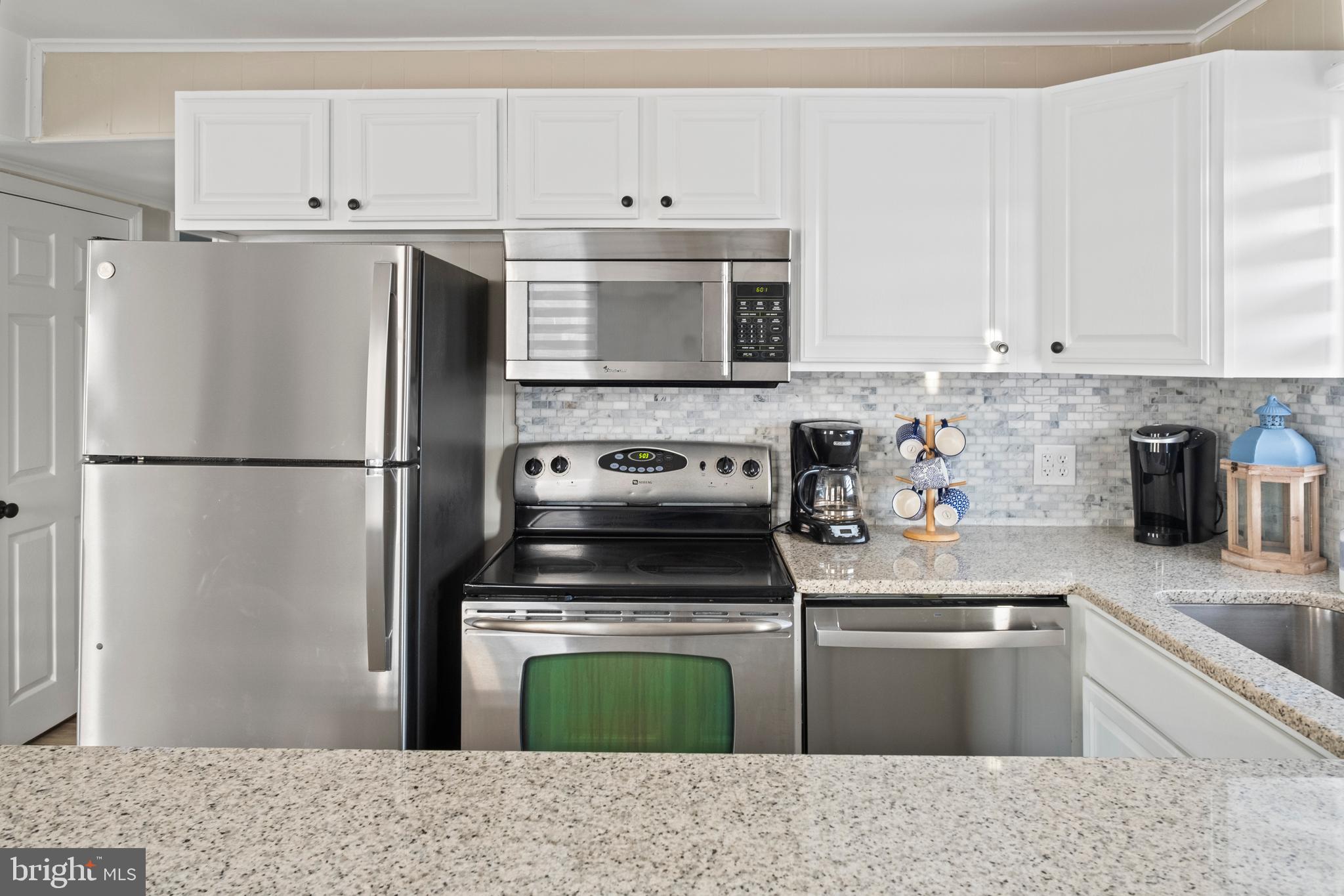 170 Captains Quarters Road, Unit 201 Ocean City, MD 21842 - Photo 59 of 65 a kitchen with granite countertop a refrigerator stove and sink