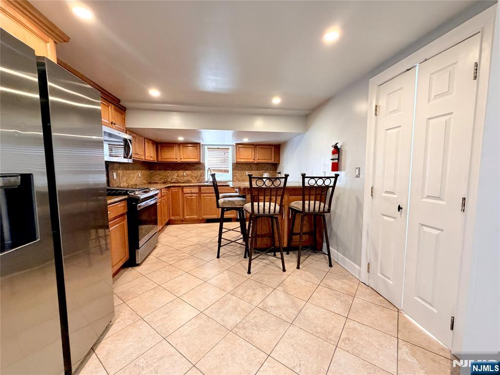 227 Washington Avenue Hackensack, NJ 07601 - Photo 5 of 33 a open kitchen with stainless steel appliances kitchen island granite countertop a table chairs and a refrigerator