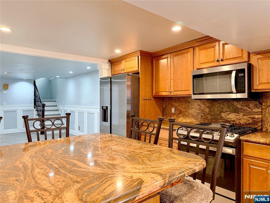 227 Washington Avenue Hackensack, NJ 07601 - Photo 7 of 33 a kitchen with stainless steel appliances kitchen island granite countertop a stove a sink a microwave a dining table and chairs with wooden floor