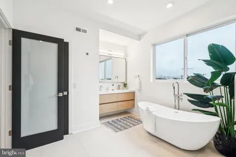 a bathroom with a granite countertop tub a sink and a large mirror