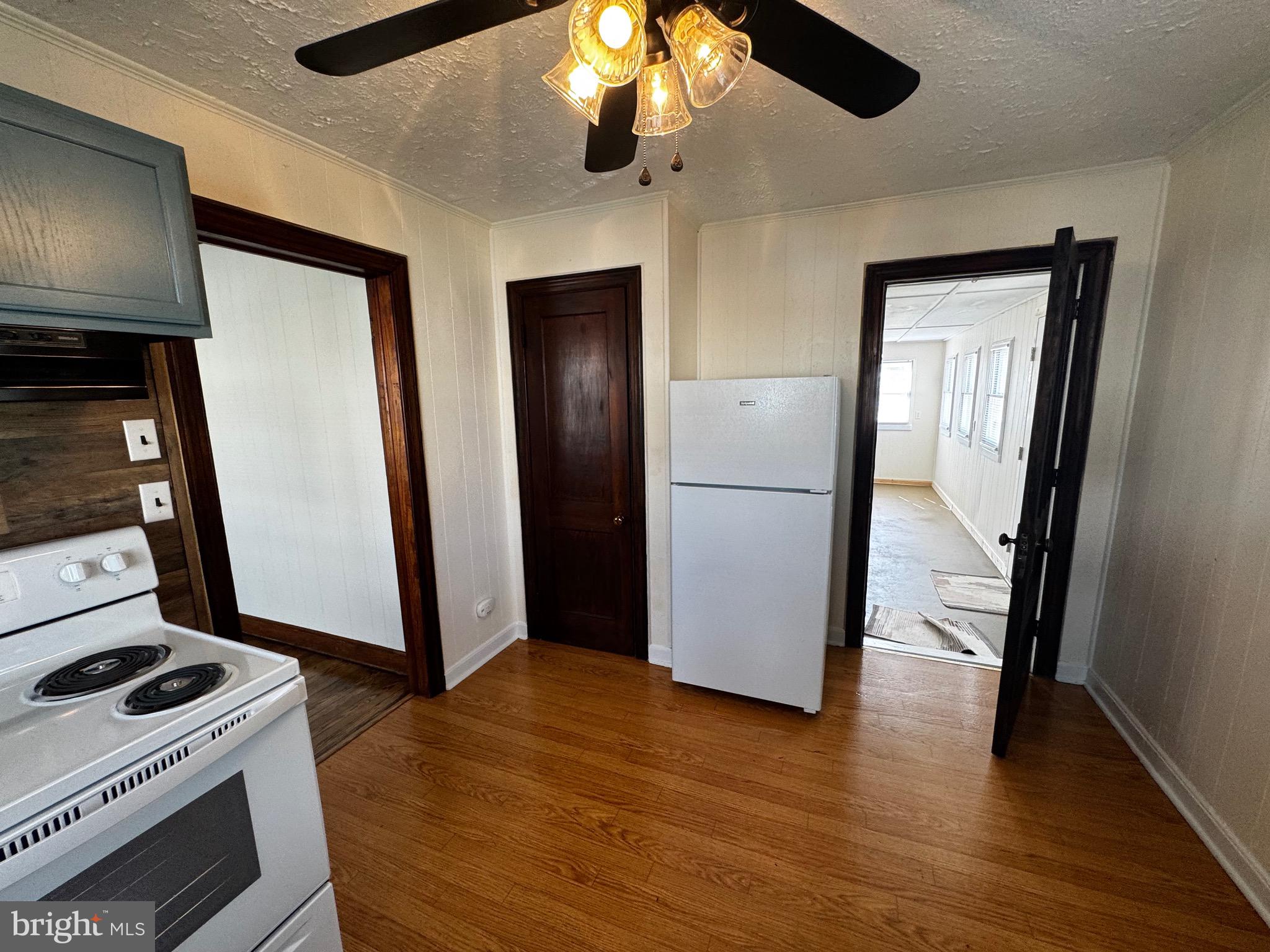 121 Center Street Mount Jackson, VA 22842 - Photo 25 of 46 a view of a refrigerator in kitchen and an empty room with wooden floor