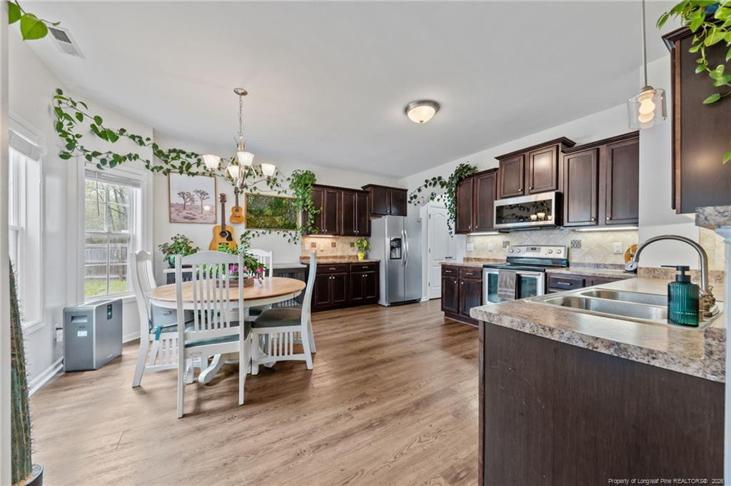 594 Allegiance Street Raeford, NC 28376 - Photo 12 of 49 a kitchen with stainless steel appliances granite countertop a stove top oven a sink dishwasher a dining table and chairs with wooden floor