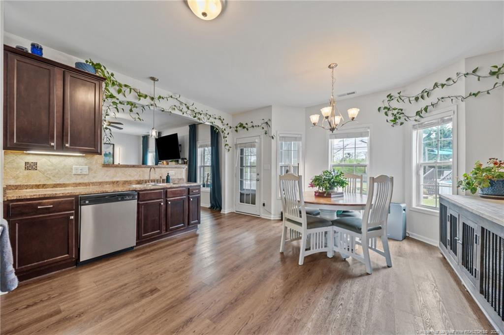 594 Allegiance Street Raeford, NC 28376 - Photo 9 of 49 a open kitchen with granite countertop a stove a sink dishwasher a dining table and chairs with wooden floor