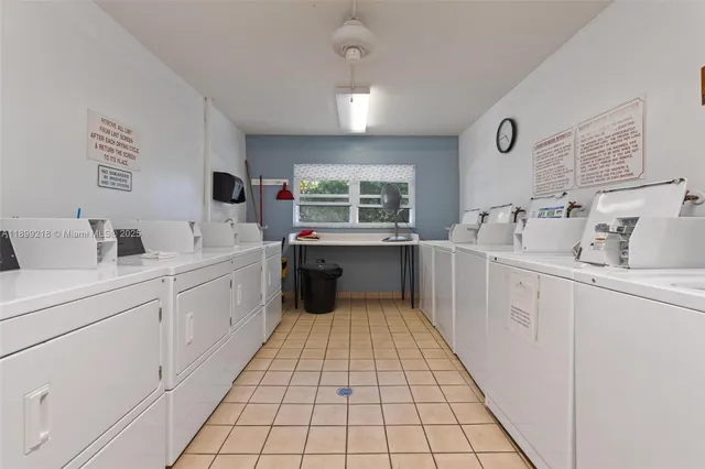 a large white kitchen with a sink a window and stainless steel appliances