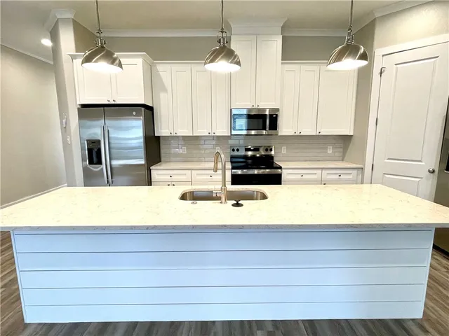a kitchen with kitchen island a counter top space a sink stainless steel appliances and cabinets