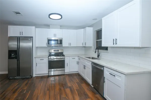 a kitchen with granite countertop a sink cabinets and stainless steel appliances
